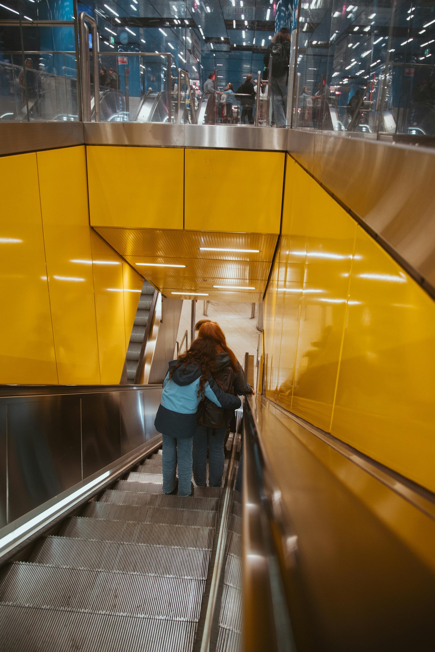 2 girls hugging on a subway escalator
